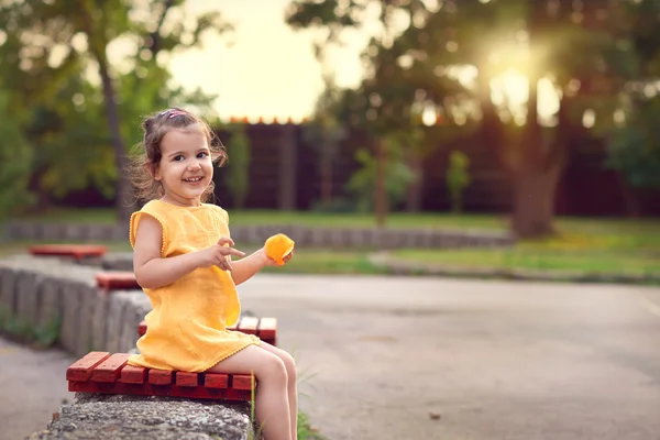 Usměvavá holčička hraje v parku při západu slunce. — Stock fotografie