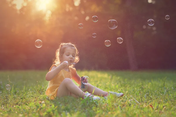 Malá dívka si hraje s mýdlem balónky. — Stock fotografie