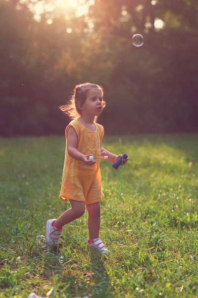 Malá dívka si hraje s mýdlem balónky. — Stock fotografie