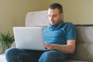 Genç adam evde çalışıyor.