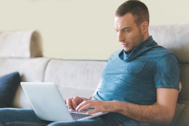 Genç adam evde çalışıyor.