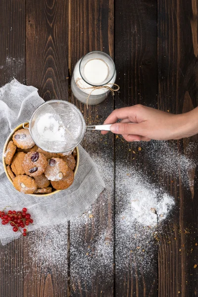 Woman's hand sprinkling icing sugar over cookies — Stock Photo, Image