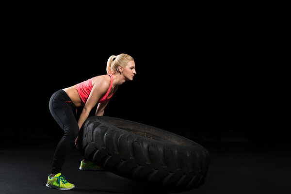 Muscular woman flip big tire as a part of Cross fit training.