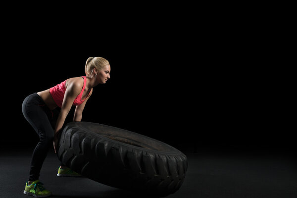 Muscular woman flip big tire as a part of Cross fit training.