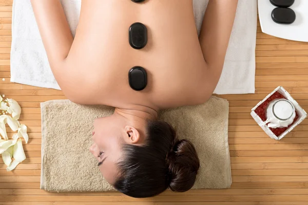 Frau genießt heißes Steinritual im Wellnesszentrum. — Stockfoto