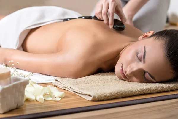 Vrouw genieten van hete stenen ritueel in Spa Center. — Stockfoto