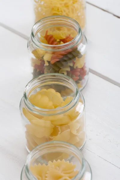 Various pasta in jars  on the wooden white  table.