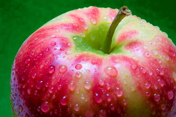 Капли воды на яблоко крупным планом на зеленом текстурированном фоне — стоковое фото