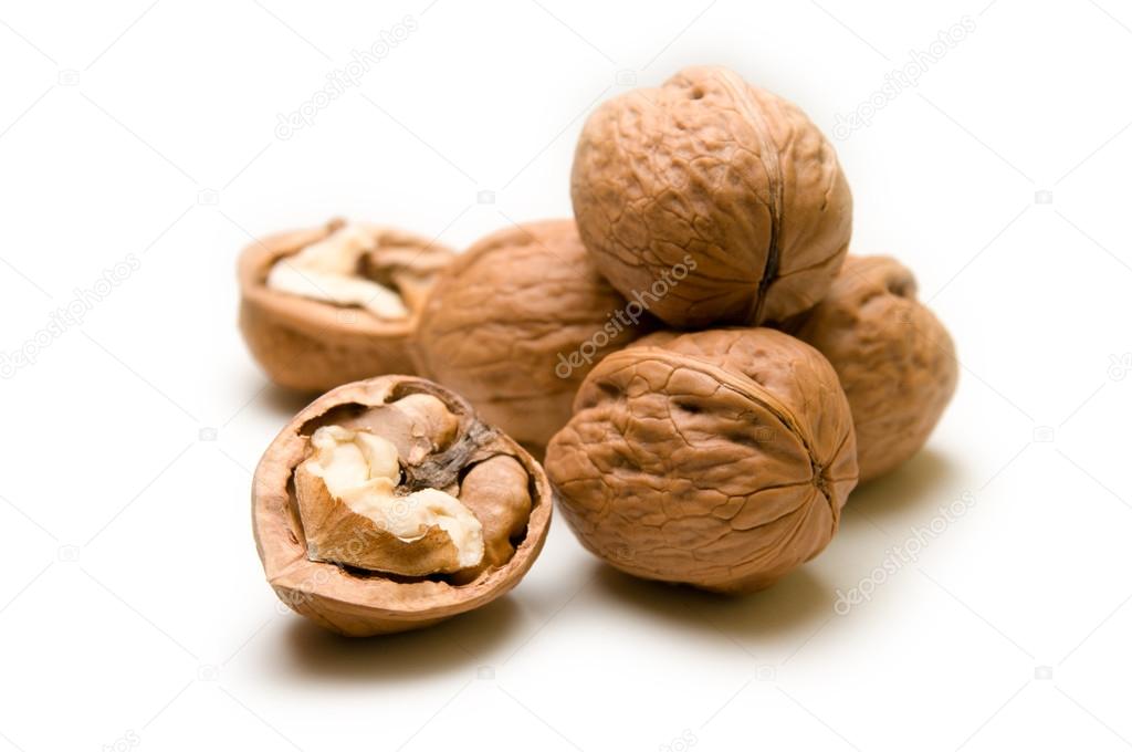 Halves and a pile of walnuts on a white background focus on half and pile is blurred