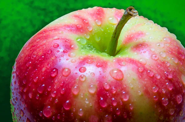 Капли воды на яблоке крупным планом на глубоком зеленом фоне — стоковое фото