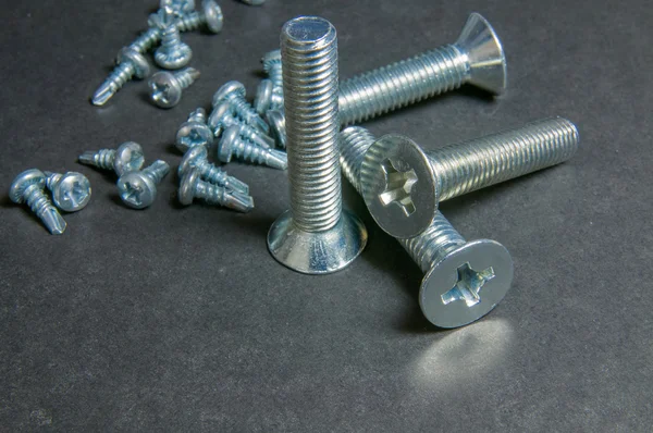 Bolts and Screws on grey. Centre upright bolt — Stock Photo, Image