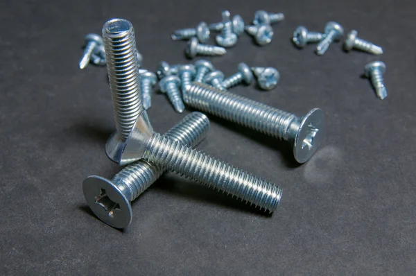 Bolts and Screws on grey. Left upright bolt — Stock Photo, Image