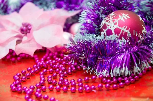 Κόκκινη Χριστουγεννιάτικη μπάλα και άλλα μωβ και ροζ διακοσμήσεις χριστουγεννιάτικων δέντρων σας σε κόκκινο φόντο — Φωτογραφία Αρχείου