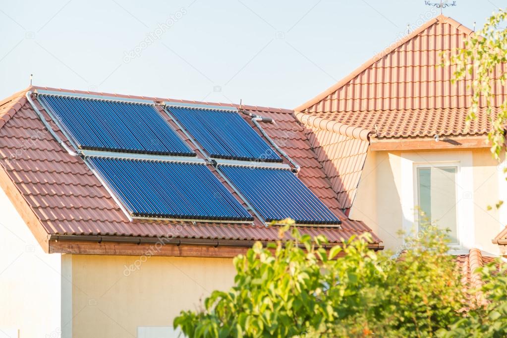 Vacuum collectors- solar water heating system on red roof of the house.