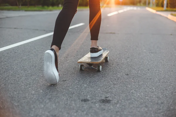 Jonge skateboarder benen rijden op skateboard voor de zon — Stockfoto