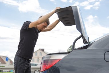 Araba yolda bozuldu. Adam araçları çekmek için bagajı açtı.