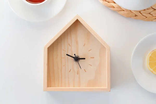 夕食の時間だ。白い背景に隔離された家の形をした木製の時計。最小限のコンセプト。平置きだ。トップ表示. — ストック写真