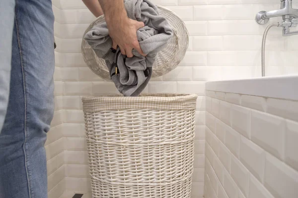 Homem coloca roupas sujas usadas em uma cesta de roupa suja. — Fotografia de Stock