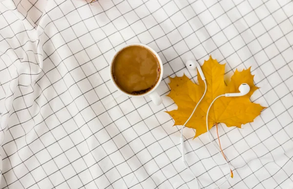 Composición de otoño. Taza de café, hojas de otoño y auriculares en tela blanca a cuadros. Plano, vista superior, espacio para copiar — Foto de Stock