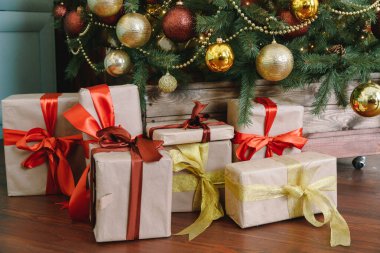 Kırmızı arka planda hediyeleri olan Noel ağacı.
