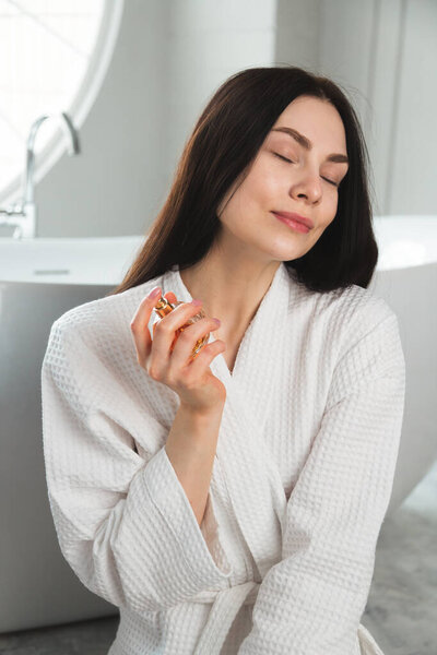 Милая молодая женщина с бутылкой духов в руке. Концепция косметики