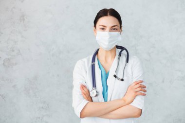 Maskeli, steteskoplu genç bayan doktor. Kafkas esmer.