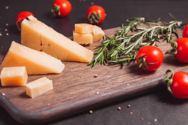 Parmesan peyniri, taze domates ve tahta üzerinde bitkiler.