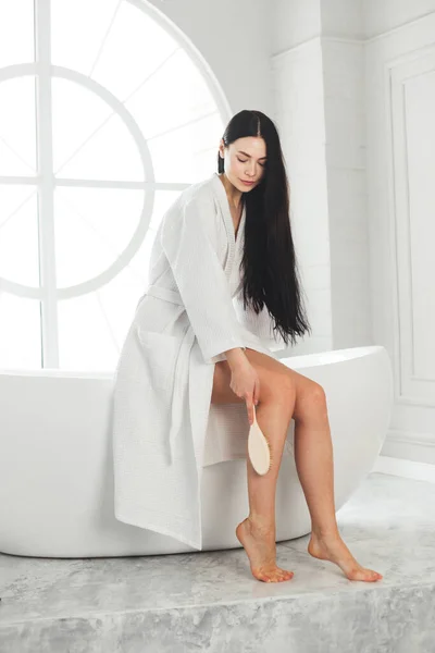 Donna utilizzare spazzola massaggio pelle sulla gamba per aumentare la circolazione e disintossicare — Foto Stock