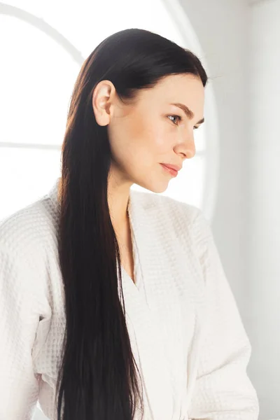 Hermosa cara de mujer retrato natural sin cosméticos. mujer morena en spa vestida con albornoz blanco. Vista del perfil. —  Fotos de Stock