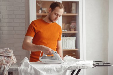 Evdeki ütü masasında çocuk çarşaflarını ütüleyen genç adam.