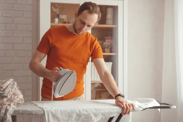 Joven planchando sábanas para niños en la tabla de planchar en casa — Foto de Stock