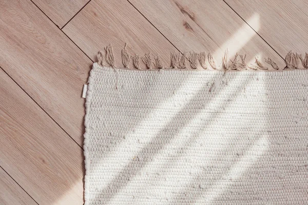 Tapete bege de vime no chão de parquet de madeira com luz solar, vista superior. — Fotografia de Stock