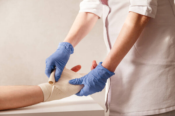 Doctor imposes an elastic bandage to the patient wrist. Rehabilitation after sprain