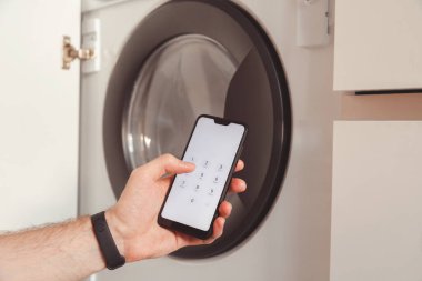 Adam kontrol etmek ve çamaşır makinesini çalıştırmak için cep telefonunu kullanıyor. Akıllı ev sistem aygıtları