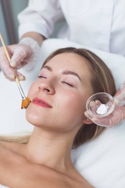 Güzellik uzmanı genç bayana yüz maskesi takıyor.