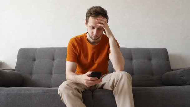 Procrastination. Běloch s mobilním telefonem doma na gauči — Stock video