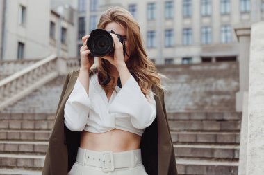 Dışarıdaki kamerayla yüzünü örten kadın fotoğrafçının portresi.