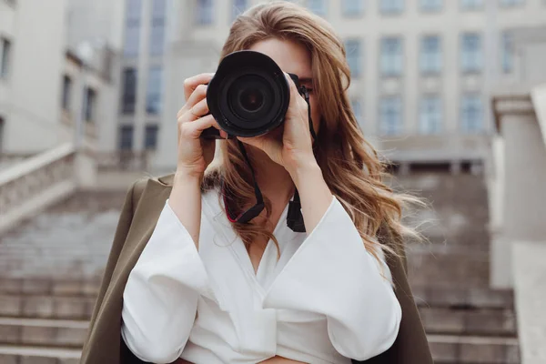 Portrait of woman photographer covering her face with camera outdoors — Stock Photo, Image