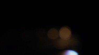 Siyah arkaplanda hareket eden küçük bulanık ışıklar .