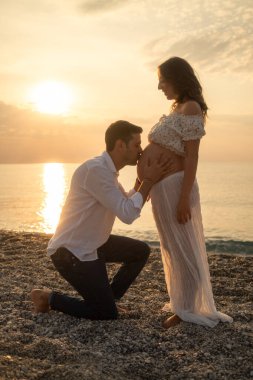 Bir çift gün batımında bebek paylaşımı bekliyor..