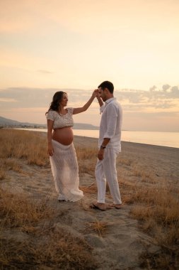 Bir çift gün batımında bebek paylaşımı bekliyor..