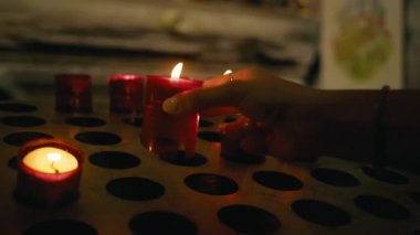 Kendini adamış bir insanın elleri sunar ve kutsal bir mum yakar..