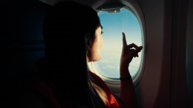 Bir kadın uçağın penceresinden mavi gökyüzüne hayran..