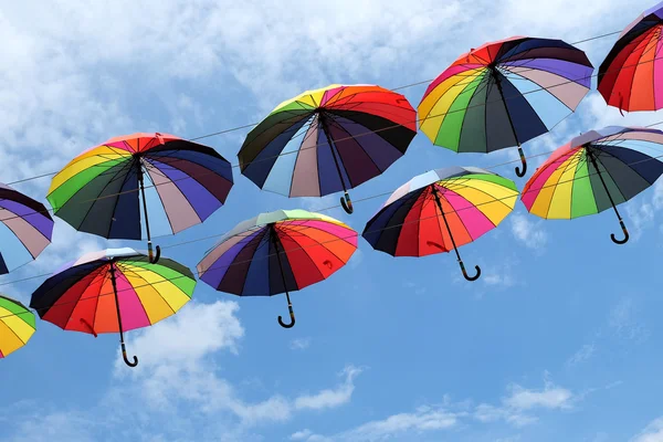 Цветные зонтики с цветами радуги в голубом небе — стоковое фото