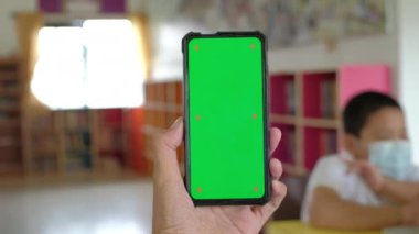 Krom tuşlu, yeşil ekran ekranlı, el kameralı akıllı telefonu tutan adam..