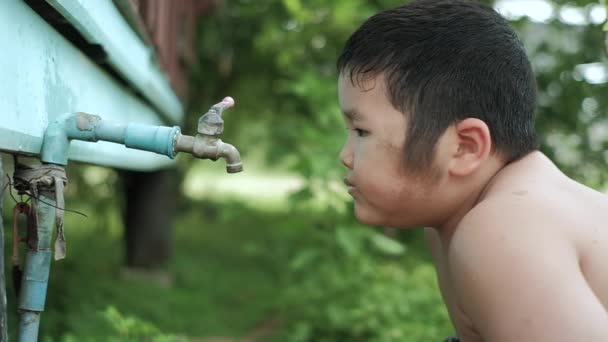 水道水から屋外で新鮮な水を飲むアジアの少年のスローモーション 水の概念を保存 — ストック動画