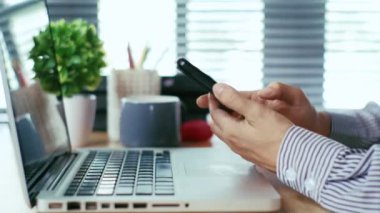 İş kadını elleri ofis masasında akıllı telefon kullanıyor..