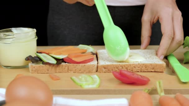 女人的手在全麦面包上撒色拉膏 以便在木制切菜板上做出健康的三明治配方 — 图库视频影像
