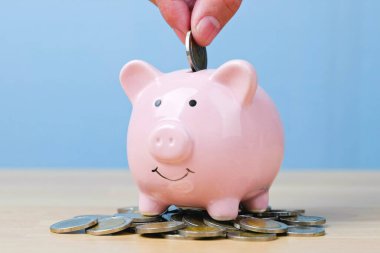 Para biriktirmek, zenginlik ve finansal konsept için domuzcuğa para yatıran bir adam..