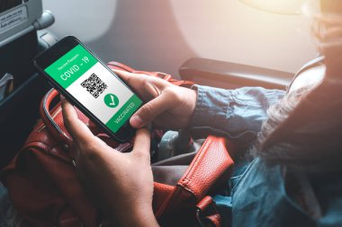 Kadın eli covid-19 salgını sırasında seyahat için cep telefonunda dijital sağlık pasaportu, covid-19 için aşı pasaportu, sağlık ve gözetim kavramları kullanıyor..